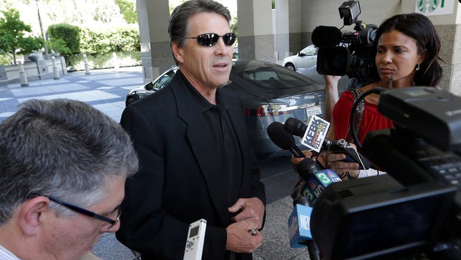 Texas Gov. Rick Perry, center, talks to reporters after driving up in a Tesla Motors Type S electric car in Sacramento, Calif., on June 19, 2014.